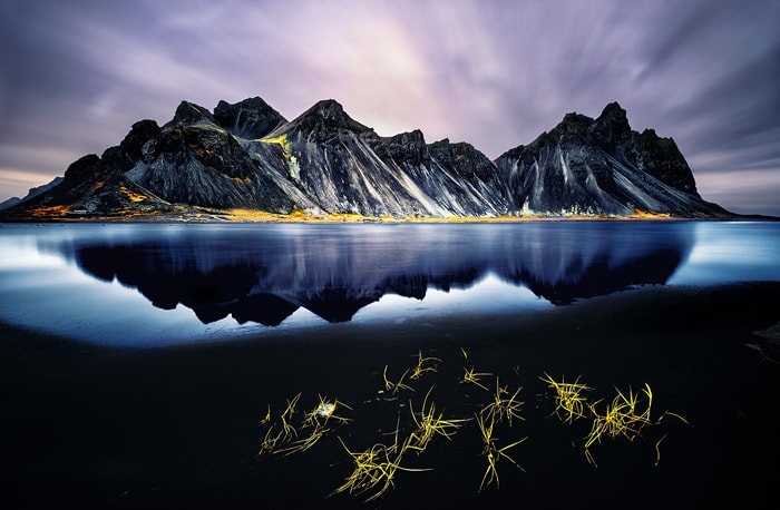 Vestrahorn Iceland is one of the most photographed mountains on the island. Located on the Stokksnes peninsula, its steep slopes reaching a flat lagoon and small black dunes create a natural wonder and one of the most beautiful Icelandic landscapes.