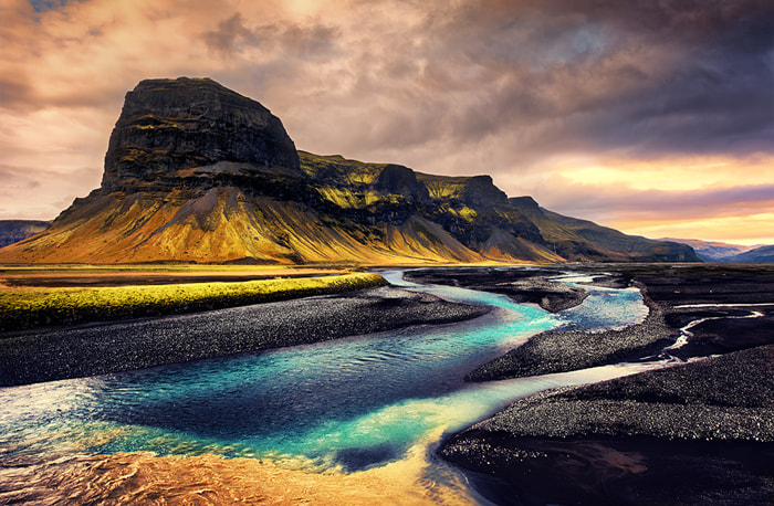 a big mountain with a colorful river in iceland